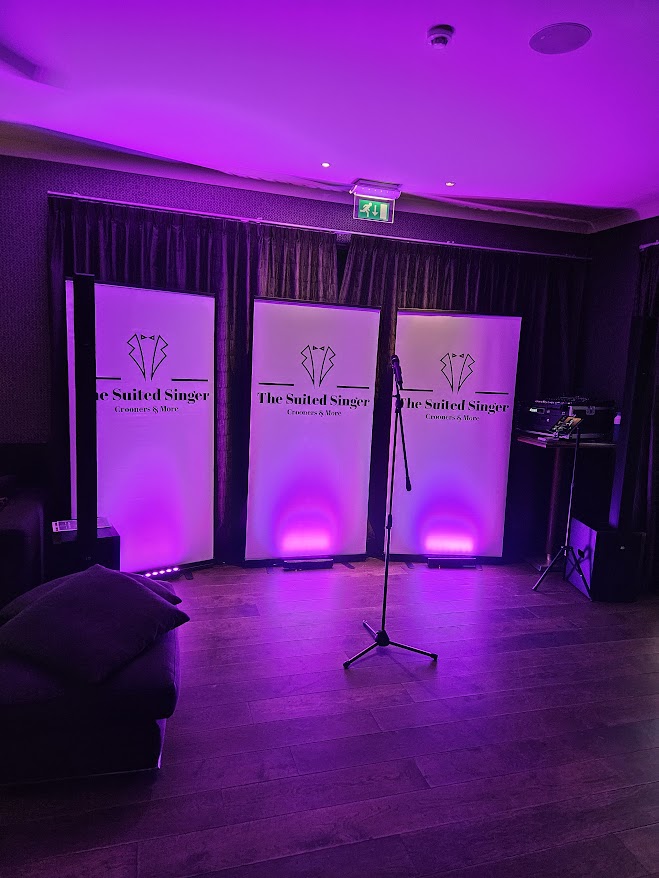 "Professionele stageset van The Suited Singer met eigen geluidsinstallatie en sfeervolle verlichting, geschikt voor evenementen tot 200 personen. Inclusief in de boeking voor een complete ervaring in geluid en ambiance.